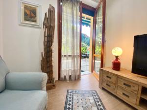 Una sala de estar con televisión y un sofá. en CasaViva - Trilo with patio in Santa Margherita L., en Santa Margherita Ligure