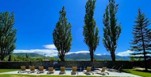 Hotel Fontanals Golf في Soriguerola: مجموعة من الكراسي والأشجار مع الجبال في الخلفية