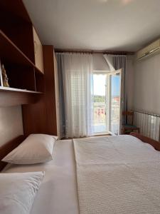 a bedroom with two beds and a large window at Apartments and Rooms Jasna in Hvar