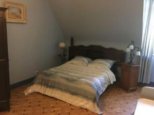 Schlafzimmer mit einem großen Bett mit einem Kopfteil aus Holz in der Unterkunft La Forge De La Coudraie in Pleugueneuc