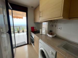 a small kitchen with a washing machine and a window at Sea view pool apartment Mojon hills in Isla Plana