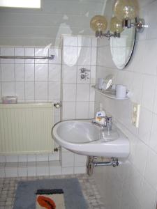a white bathroom with a sink and a mirror at Ferienwohnung am Busterbach in Seebach