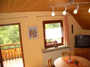 a dining room with a table and a television at Ferienwohnung am Busterbach in Seebach