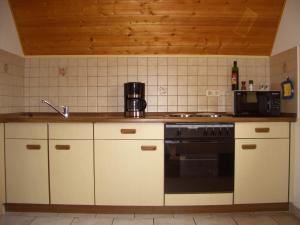 una cocina con armarios blancos y horno negro en Ferienwohnung am Busterbach, en Seebach