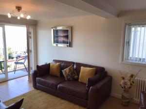 a brown leather couch in a living room with a window at Beautiful 3-Bed Apartment in Gourock in Gourock