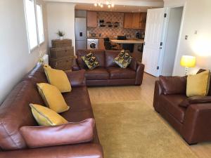 a living room with a brown leather couch and yellow pillows at Beautiful 3-Bed Apartment in Gourock in Gourock
