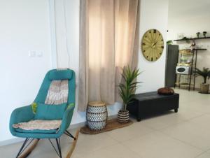 a living room with a blue chair and a clock at Ten Steps To The sea 4BR And Balcony in Bat Yam