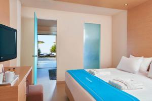 a bedroom with a bed and a television and a balcony at The Island Hotel - Adults Only - in Gouves