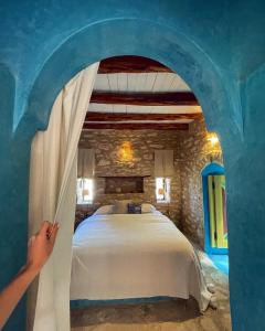 uma pessoa a chegar a uma cama num quarto em Atlantis 12, Maison d'hôtes et d'art em Essaouira