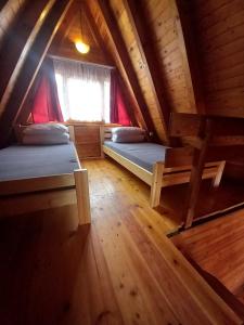 Cette chambre mansardée comprend 2 lits et une fenêtre. dans l'établissement Domki Letniskowe KORMORAN, à Kąty Rybackie