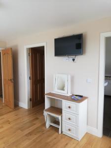 een kamer met een witte dressoir met een tv aan de muur bij Glenmore House - ROOM ONLY in Doolin