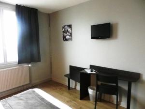 a bedroom with a desk and a tv on the wall at Hôtel Du Port in Les Sables-d'Olonne