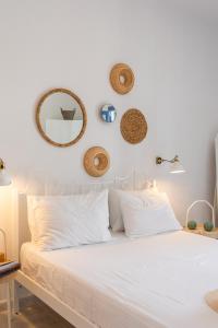 a white bed with white pillows and mirrors on the wall at Anamnisi Studio in Adamantas