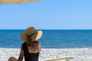 a woman sitting on the beach with an umbrella at Amalthia Villa, Heated Pool & Walk to the Beach, By ThinkVilla in Tavronitis