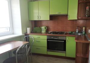 a kitchen with green cabinets and a stove and a table at Baltijos 1 Apartament in Klaipėda