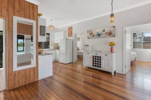 cocina y sala de estar con electrodomésticos blancos y suelo de madera en Phegans Bay Waterfront Retreat en Blackwall