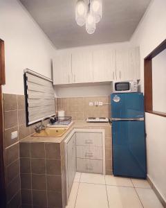 a kitchen with a blue refrigerator and a sink at Résidence Palms Abidjan in Abidjan