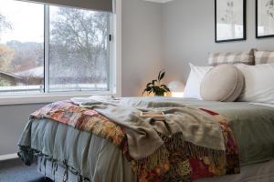 ein Bett mit einer Decke in einem Zimmer mit einem Fenster in der Unterkunft Little Olive in Kyneton