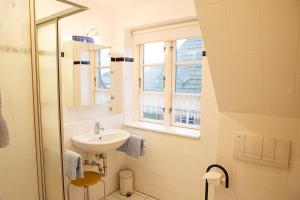 La salle de bains blanche est pourvue d'un lavabo et d'une fenêtre. dans l'établissement Friesennest, à Oldsum