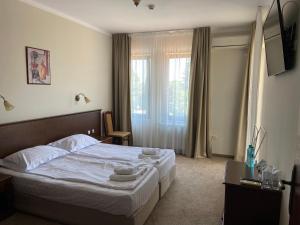 um quarto com uma cama com lençóis brancos e uma janela em Villa Maria Revas em Sunny Beach