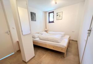 una piccola camera da letto con un letto con lenzuola bianche di Appartement 4 couchages à proximité du plan d'eau a Saint-Sauveur