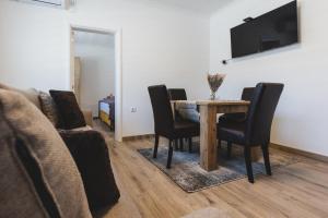 a dining room with a table and chairs and a couch at ALFA Apartmani in Subotica