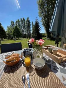 une table avec une assiette de nourriture et un vase de fleurs dans l'établissement Le Vieil Home, au pied de la cité médiévale, à La Haute-Chapelle