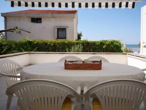 a white table with chairs and a basket on top of it at Diklo beach apartments 1 in Zadar