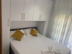 1 dormitorio con 1 cama con armarios blancos y almohadas amarillas en Julia Apartments en Vlorë