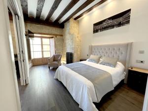 a bedroom with a large bed and a chair at Apartamentos El Mirador del Poeta in Salamanca
