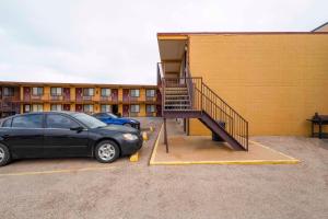 un coche negro estacionado junto a un edificio con una escalera en Oyo Hotel Odessa TX, East Business 20 en Odessa