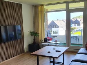 a living room with a table and a large window at Am Strand in Harrislee