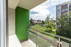 a balcony with a green wall and a view of a park at Hotel Krystal in Hodonín