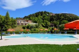 uma piscina com cadeiras e guarda-sóis em Hotel Pineta Campi em Tremosine Sul Garda