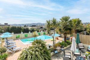 an outdoor pool with chairs and umbrellas and palm trees at The Cimon in Torquay