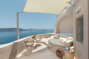 a balcony with a table and chairs and the ocean at The Exotic Cave Suite in Oia
