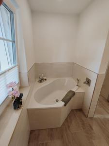 ein Badezimmer mit einer Badewanne und einer Vase aus Blumen in der Unterkunft Ferienwohnung - Am Tannenwald in Burg Kauper