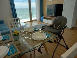 comedor con mesa de cristal y silla en Promenada Sea View with private parking, en Mamaia Nord – Năvodari