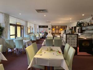 ein Esszimmer mit weißen Tischen und Stühlen sowie ein Restaurant in der Unterkunft Hotel Im Kräutergarten in Cursdorf