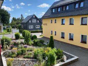 einen Garten vor einem gelben Gebäude in der Unterkunft Hotel Im Kräutergarten in Cursdorf
