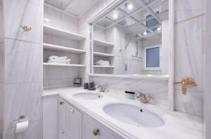 een witte badkamer met een wastafel en een spiegel bij Deco Marble Apt with Acropolis view in Athene