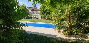 una piscina frente a una casa con árboles en Château de Grandmont - Escale authentique au coeur des vignes, en Blacé