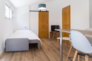 - une chambre avec un lit, une table et des chaises dans l'établissement Longère pierres/modernité proche mer/la guittière, à Talmont-Saint-Hilaire