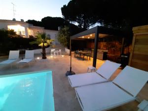 einen Pool mit weißen Stühlen und ein Haus in der Unterkunft VILLA RASOA chambre LOVE in Cap d'Agde