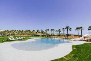 a large swimming pool with palm trees in the background at Mangia's Selinunte Resort in Marinella di Selinunte