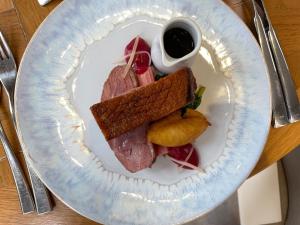 a plate of food with a sandwich and a cup of sauce at Oakley Hall Hotel in Basingstoke