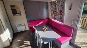 Habitación pequeña con sofá rosa y mesa. en Mobil-Home 6 pers sur une grande parcelle, proche Paris camping 3 étoiles en Mirgaudon