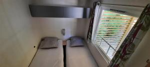 Habitación pequeña con 2 camas y ventana en Mobil-Home 6 pers sur une grande parcelle, proche Paris camping 3 étoiles, en Mirgaudon