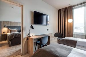 a hotel room with two beds and a desk at Quality Airport Hotel Værnes in Stjoerdal