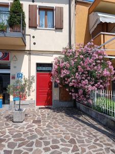 un bâtiment avec une porte rouge et des fleurs devant lui dans l'établissement Bed & Breakfast Lucy, à Bardolino